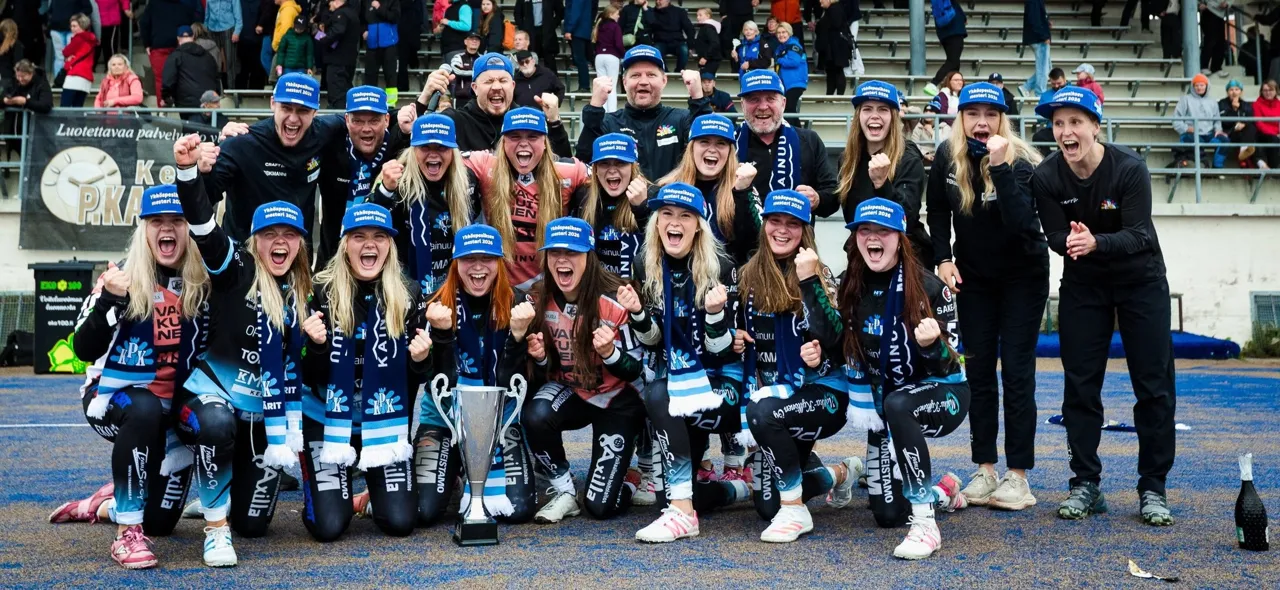 Kajaanin Pallokerhon naisten joukkue juhlii kiertopalkinnon kanssa kentällä ratkaisuottelun jälkeen.